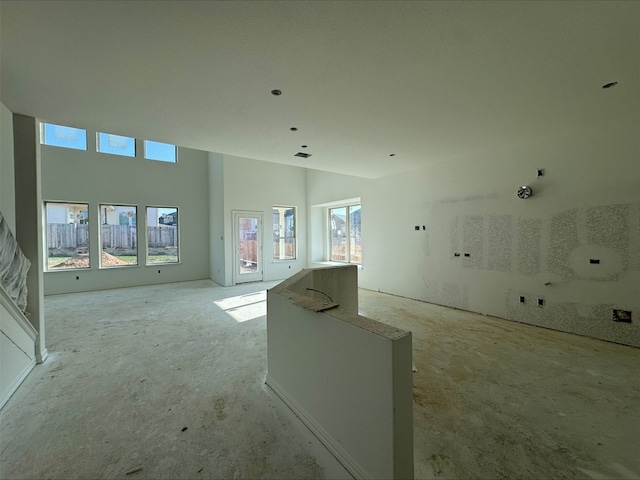 unfurnished living room featuring a towering ceiling