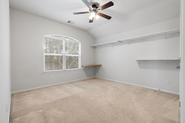 walk in closet with light carpet, vaulted ceiling, and ceiling fan