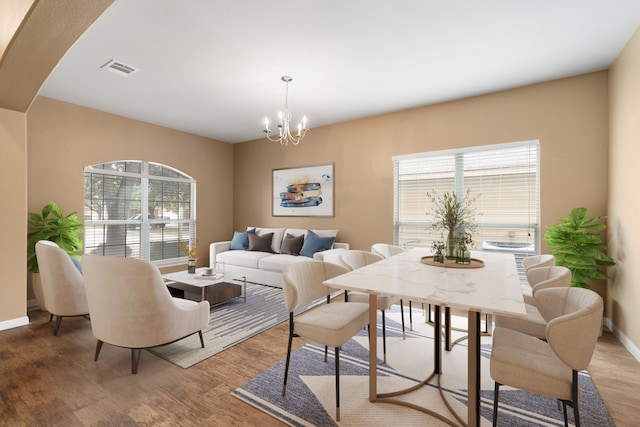 dining area with hardwood / wood-style floors and a notable chandelier