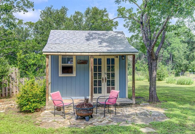 view of outdoor structure with french doors, a yard, and a fire pit