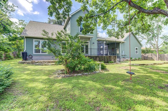 rear view of property with a lawn and a sunroom