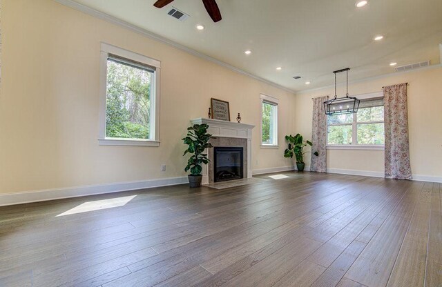 unfurnished living room with ornamental molding, plenty of natural light, dark wood-type flooring, and ceiling fan