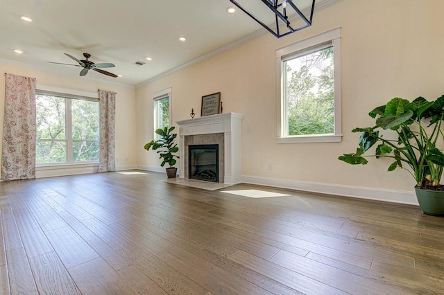 unfurnished living room featuring a tile fireplace, ceiling fan, a healthy amount of sunlight, and wood-type flooring