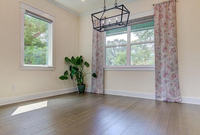 empty room with a chandelier, dark hardwood / wood-style floors, and ornamental molding