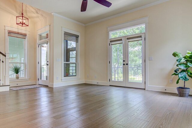 doorway with hardwood / wood-style flooring, ceiling fan with notable chandelier, crown molding, and french doors