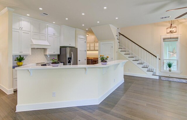 kitchen featuring white cabinets, a spacious island, stainless steel refrigerator with ice dispenser, and a breakfast bar area