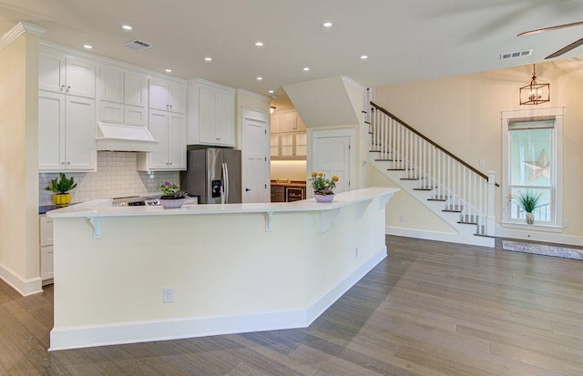 kitchen featuring a large island, a kitchen bar, stainless steel fridge, and white cabinets