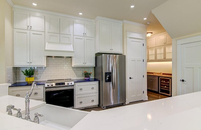 kitchen with white cabinets, wine cooler, light stone counters, and appliances with stainless steel finishes