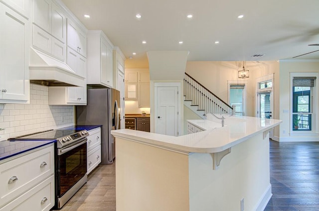 kitchen with white cabinets, a kitchen island with sink, appliances with stainless steel finishes, and a breakfast bar area