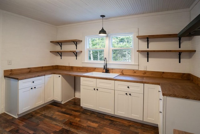 kitchen featuring butcher block counters, sink, decorative light fixtures, dark hardwood / wood-style flooring, and white cabinetry