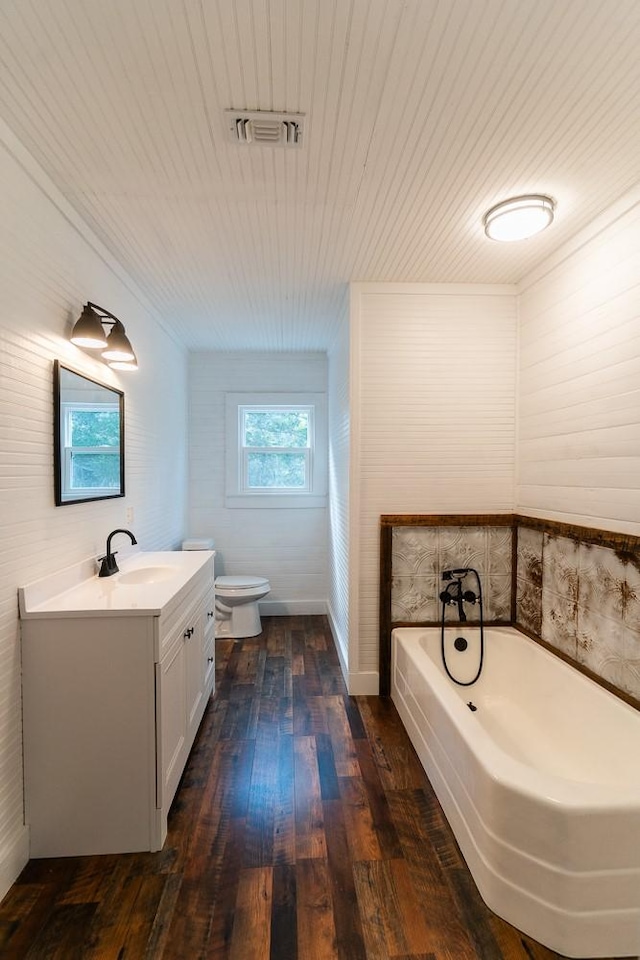 bathroom with hardwood / wood-style floors, vanity, toilet, and a bathing tub