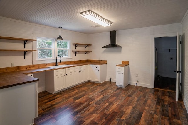 kitchen with dark hardwood / wood-style flooring, wall chimney exhaust hood, sink, pendant lighting, and white cabinetry