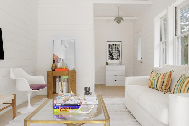 living area featuring beamed ceiling and wooden walls