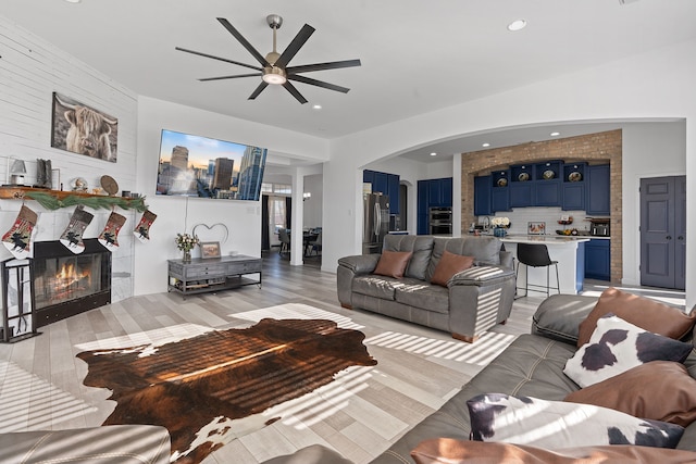 living room featuring ceiling fan, arched walkways, a fireplace, and recessed lighting