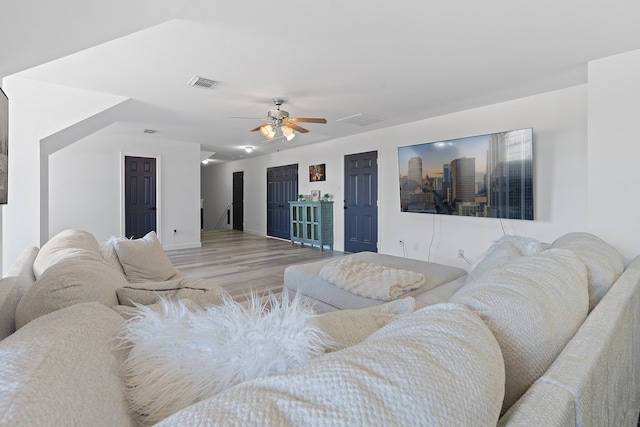 living area with light wood-type flooring, visible vents, and a ceiling fan