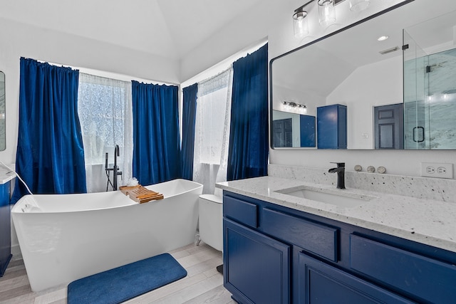 bathroom featuring lofted ceiling, wood finished floors, a freestanding tub, and vanity