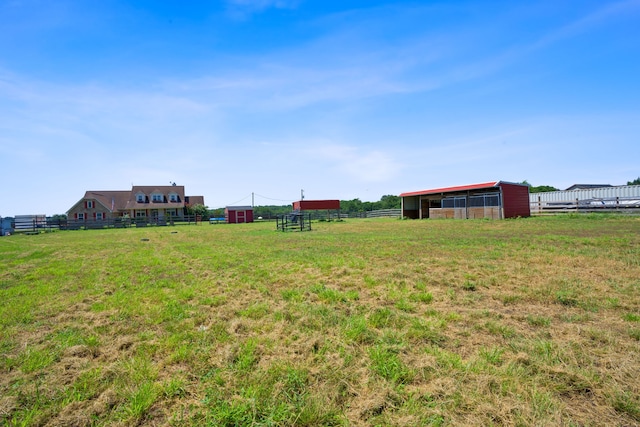 view of yard featuring a rural view, fence, and an outdoor structure