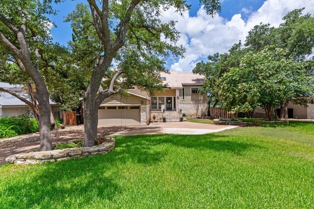 view of front of property featuring a garage, driveway, stone siding, and a front lawn