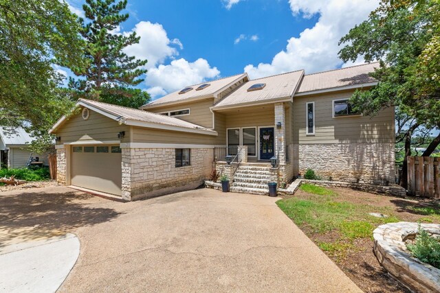 view of front of property with fence, an attached garage, driveway, and stone siding