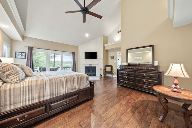 bedroom featuring multiple windows, access to exterior, a large fireplace, dark wood finished floors, and high vaulted ceiling
