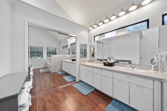 bathroom featuring hardwood / wood-style flooring, vanity, a bathing tub, and vaulted ceiling