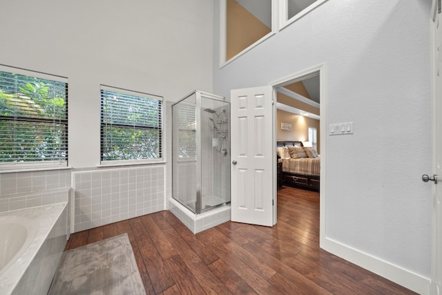 bathroom with wood-type flooring, independent shower and bath, and a high ceiling