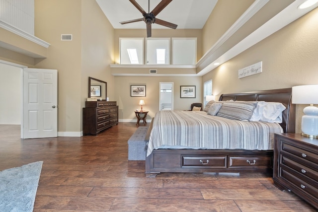 bedroom with wood-type flooring, high vaulted ceiling, visible vents, and baseboards