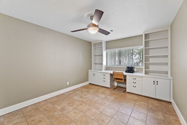 unfurnished office featuring ceiling fan, built in desk, a textured ceiling, and light tile patterned floors