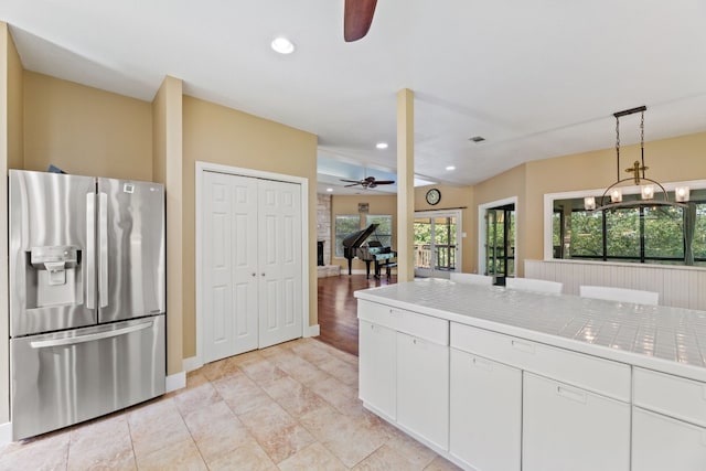 kitchen with decorative light fixtures, white cabinets, stainless steel fridge, tile counters, and ceiling fan