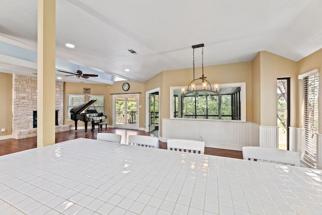 dining area with lofted ceiling, ceiling fan with notable chandelier, a fireplace, and dark hardwood / wood-style floors