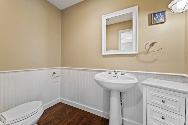 bathroom with a sink, wainscoting, wood finished floors, and toilet
