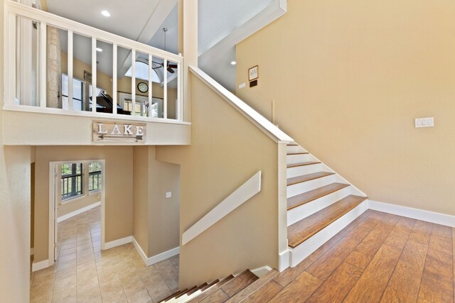 stairs with baseboards, recessed lighting, and a towering ceiling