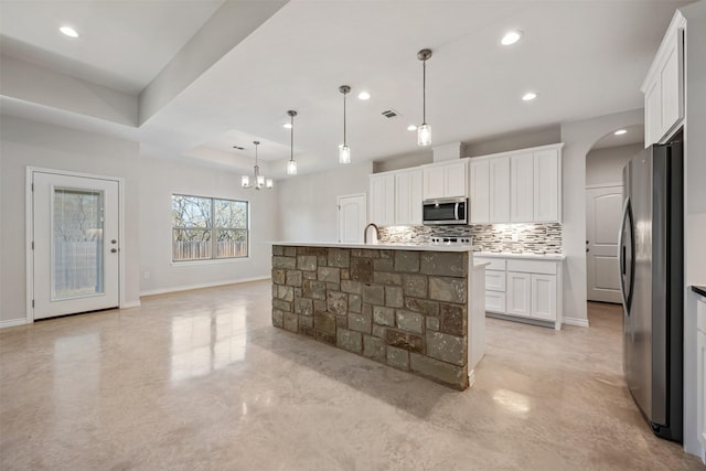 kitchen with pendant lighting, a kitchen island with sink, white cabinets, decorative backsplash, and stainless steel appliances