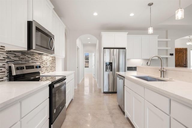 kitchen with light stone countertops, appliances with stainless steel finishes, sink, pendant lighting, and white cabinets