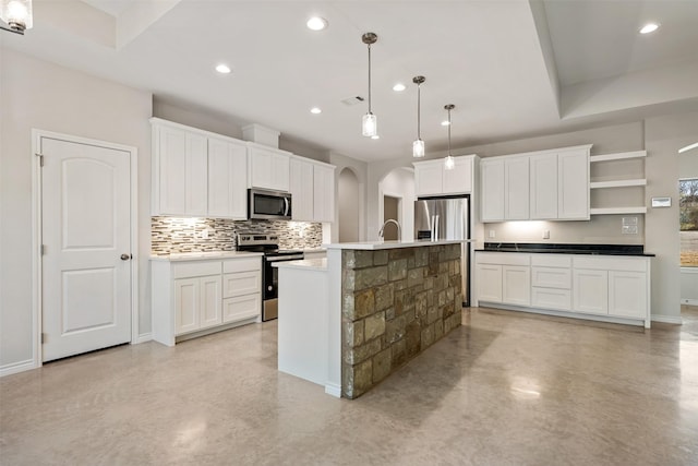 kitchen featuring sink, an island with sink, decorative light fixtures, white cabinets, and appliances with stainless steel finishes