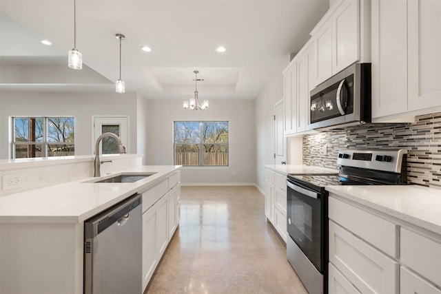 kitchen featuring white cabinetry, sink, stainless steel appliances, an inviting chandelier, and a raised ceiling