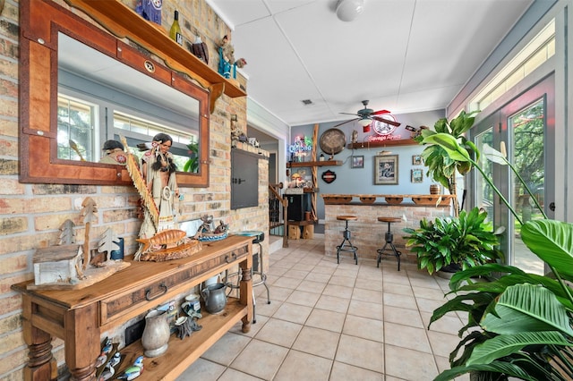 interior space featuring ceiling fan and brick wall