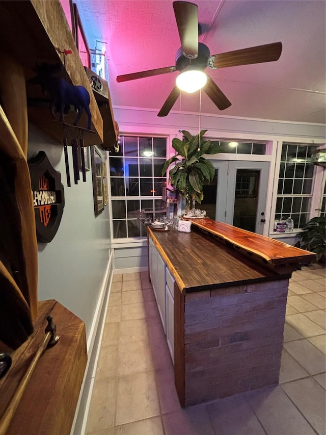 kitchen with ceiling fan, light tile patterned floors, and wooden counters