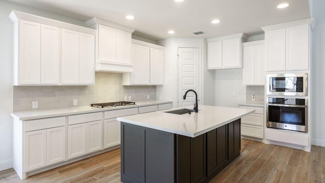 kitchen with visible vents, light wood-type flooring, appliances with stainless steel finishes, white cabinets, and a sink