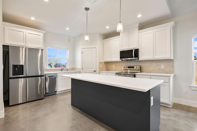 kitchen with a kitchen island, appliances with stainless steel finishes, decorative light fixtures, white cabinets, and backsplash