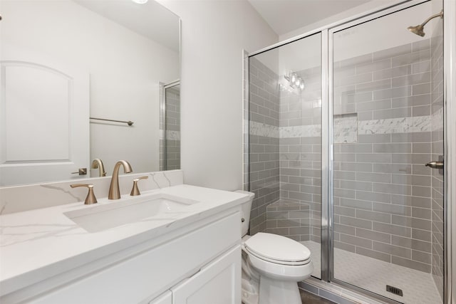 bathroom with a shower with door, vanity, and toilet