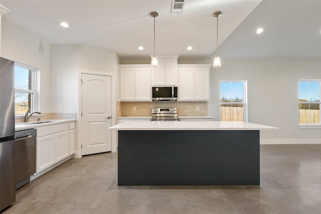 kitchen featuring sink, pendant lighting, stainless steel appliances, decorative backsplash, and white cabinets