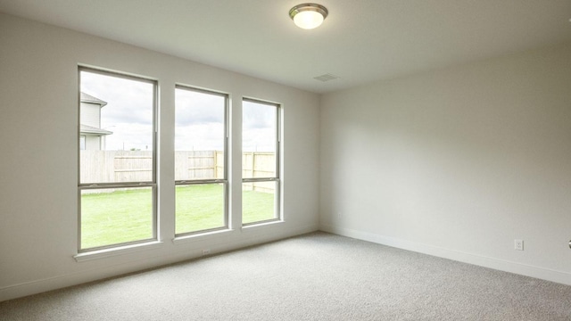 unfurnished room with healthy amount of natural light, light colored carpet, and baseboards