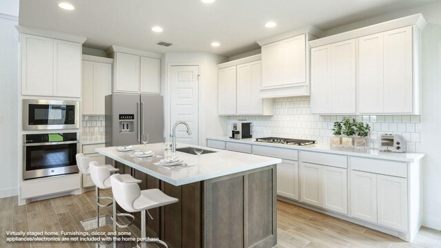 102 Iva Ln, Georgetown, TX 78628 - kitchen featuring appliances with stainless steel finishes, a sink, light wood-style floors, a kitchen bar, and recessed lighting