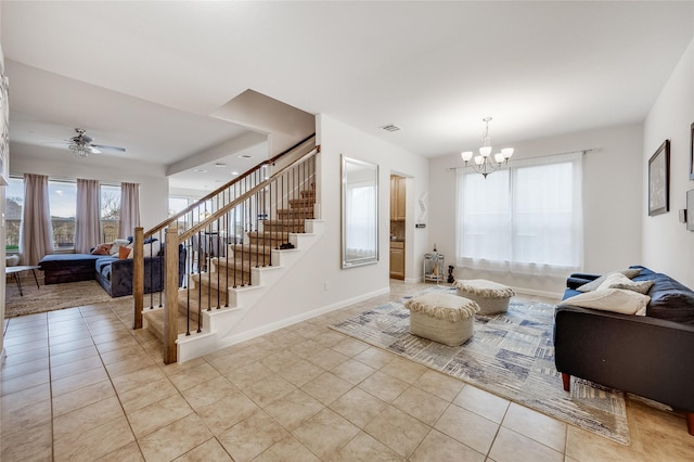 tiled living room with ceiling fan with notable chandelier