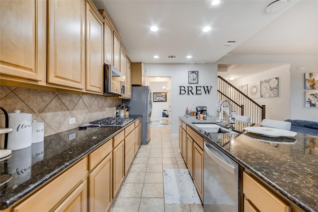 kitchen featuring appliances with stainless steel finishes, light brown cabinetry, sink, backsplash, and light tile patterned floors