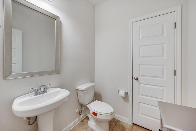 bathroom with toilet, tile patterned flooring, and sink