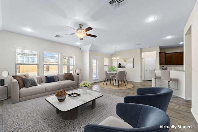 living room featuring ceiling fan with notable chandelier and dark hardwood / wood-style flooring