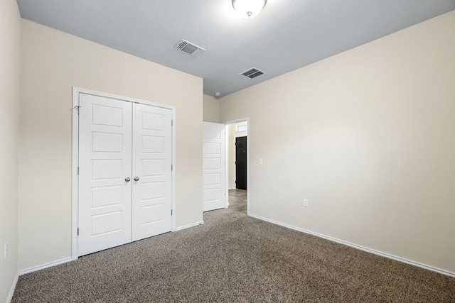 unfurnished bedroom featuring dark carpet and a closet