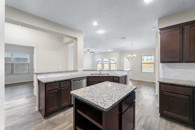 kitchen with kitchen peninsula, ceiling fan with notable chandelier, a kitchen island, and sink